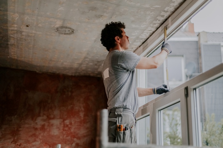 A worker installing or measuring a large window indoors in San Jose, CA